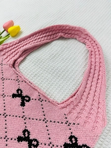 Detailed close-up of pink knit tote bag featuring black bow patterns and diamond textures