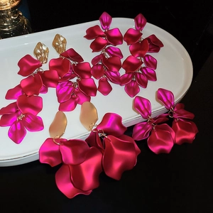 Detail of rose red petal tassel earrings with gold leaf studs on white tray