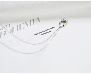 Macro view of minimalist liquid metal ear cuff with long silver fringe chain tassels