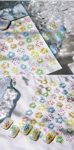 Close-up of 3D colorful flower nail stickers with textured patterns and gold foil detail