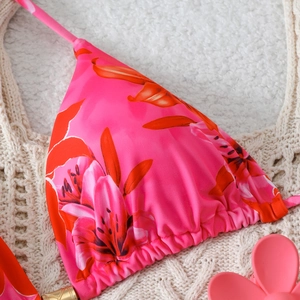 Close-up of pink bikini top with orange tropical floral print on crochet background