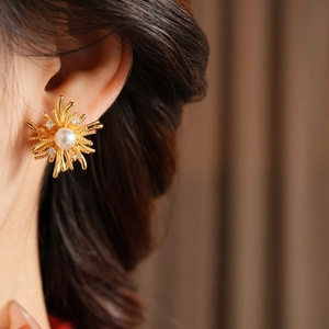 Close-up of gold starburst earrings with white pearl and crystals on a model