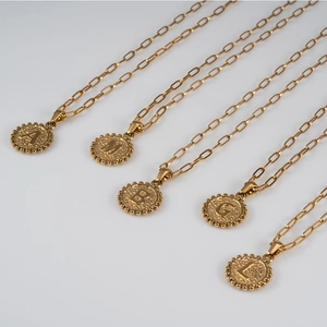 Detail of 18K gold-plated stainless steel coin pendants with hammered texture and letters