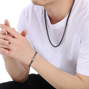 Gros plan d'un ensemble collier et bracelet noirs à chaîne de blé porté par un modèle