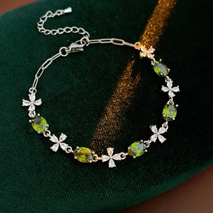 Detail of silver bracelet with green oval gems and white flower zircons on velvet