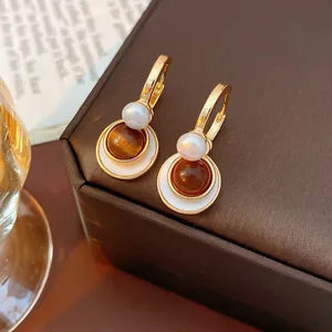 Retro hoop earrings with white pearl and brown tiger eye shell charms on a velvet box