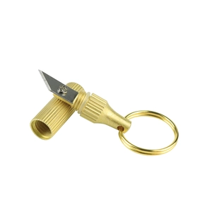 Detailed view of mini brass capsule knife with stainless steel blade and gold keychain