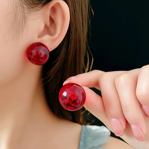 Macro detail of round dark red resin earrings featuring metallic gold foil texture