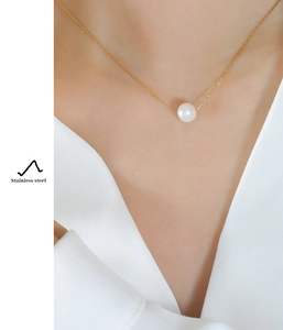 Detail of single natural freshwater pearl pendant on a gold stainless steel chain