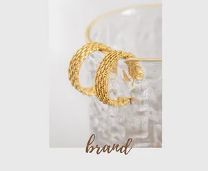 Detail of 18K gold-plated titanium earrings with woven mesh texture on glass rim