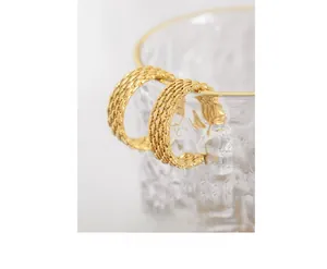 Detail of 18K gold-plated titanium earrings with woven mesh texture on glass rim