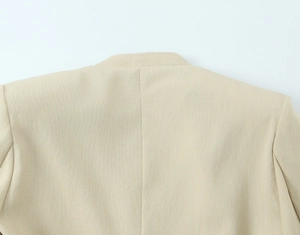 Détail de la texture tissée beige et des coutures sur le col arrière et les épaules