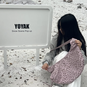 Outdoor shot of a large pink leopard print crescent bag on a snowy background