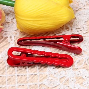 Pair of red wavy metal hair clips on white lace fabric with yellow tulips decoration