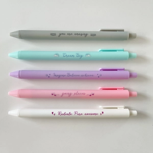 Close-up of five matte pastel gel pens featuring motivational English slogans on white background