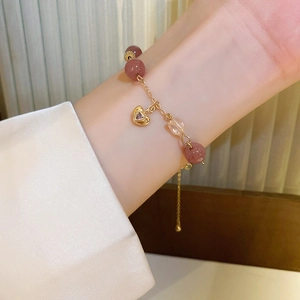 Detailed view of pink strawberry crystal bracelet with heart zircon charm on wrist