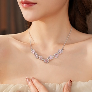 Macro view of silver necklace with pink rectangular gems and zircon floral accents