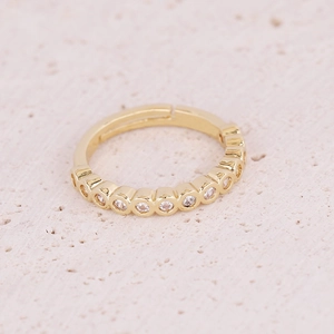 Macro shot of gold adjustable ring with row-set zircons on pink stone background