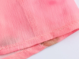 Dettaglio del tessuto in chiffon rosa tie-dye con trama traspirante e cuciture pulite