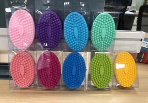 Detailed view of colorful oval silicone baby bath brushes in transparent packaging