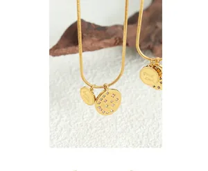 Detailed view of a gold snake chain necklace with a Good Luck disc and zircon pendant