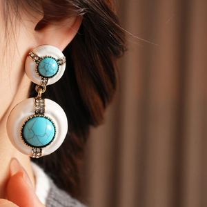 Close-up of vintage gold earrings with turquoise stones and rhinestone accents