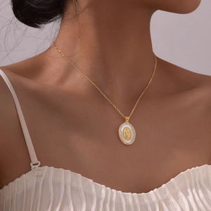 Detailed close-up of a gold oval Virgin Mary pendant with sparkling white zircon inlay