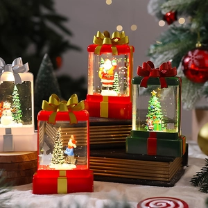 Close-up of lighted Christmas gift box lantern with Santa Claus and sparkling glitter inside