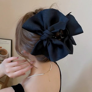 Dettaglio di una grande molletta per capelli a fiocco in raso nero su acconciatura