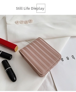 Detail view of a pink quilted mini makeup pouch with mirror on a stylish fashion background