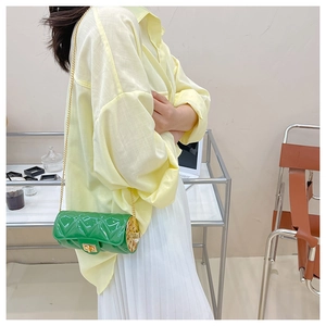 Detail of green cylinder bag with quilted texture and gold chain strap on model