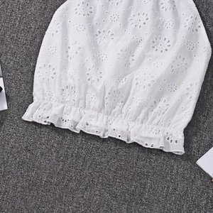 Detailed macro view of white lace embroidery and floral cutout texture on a crop top