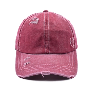 Detail of distressed red vintage baseball cap showing frayed edges and white contrast stitching