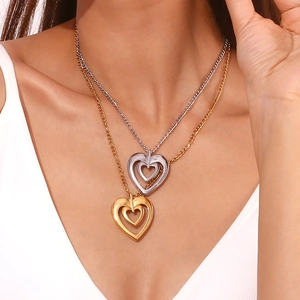 Detailed view of layered heart pendants in gold and silver finish on delicate metal chains