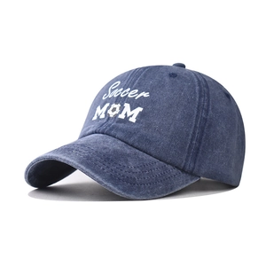 Close-up of Soccer MOM embroidery on washed denim blue baseball cap with soccer icon