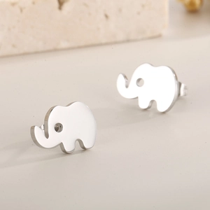 Macro shot of minimalist silver elephant stud earrings on a textured stone surface