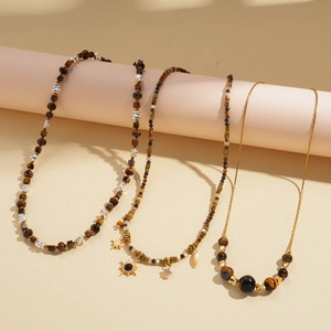 Retro bohemian necklaces with tiger eye sun and star pendants on warm background