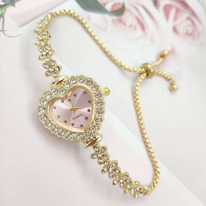 Golden heart-shaped quartz watch with rhinestones and pink dial on floral background