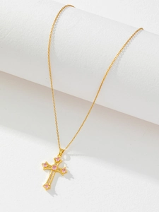 Detail of gold cross pendant with pink gemstones on a white geometric display