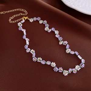 Detail of handmade beaded necklace with purple and white daisy flower patterns