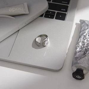 Polished stainless steel open ring with oval clear zircon on a laptop surface