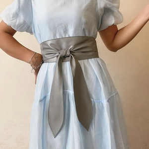 Détail de la ceinture corset grise en similicuir avec un nœud sur une robe bleue