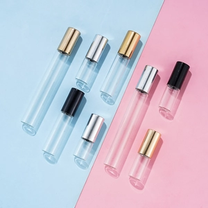 Clear glass perfume roller bottles with gold, silver, and black caps on a dual-tone background