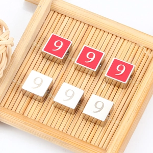Polished silver and red cube beads with number 9 engraving on a bamboo mat