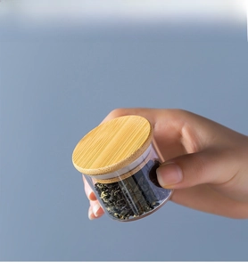 Mini portable glass tea storage jar with wood lid held in hand for travel size