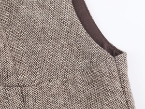 Close-up of brown tweed fabric texture and stitching details on the sleeveless vest