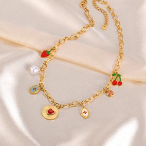 Close-up of gold necklace with fruit, heart and pearl charms on beige satin fabric