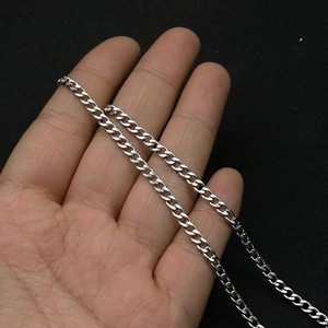 Macro detail of silver stainless steel Cuban link chain necklace with polished finish