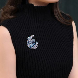 Elegant crescent moon brooch with blue crystals pinned on black knit sweater