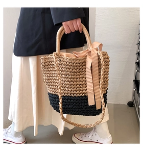 Detail of hand-woven straw bag featuring color-block design and pink silk ribbon bow